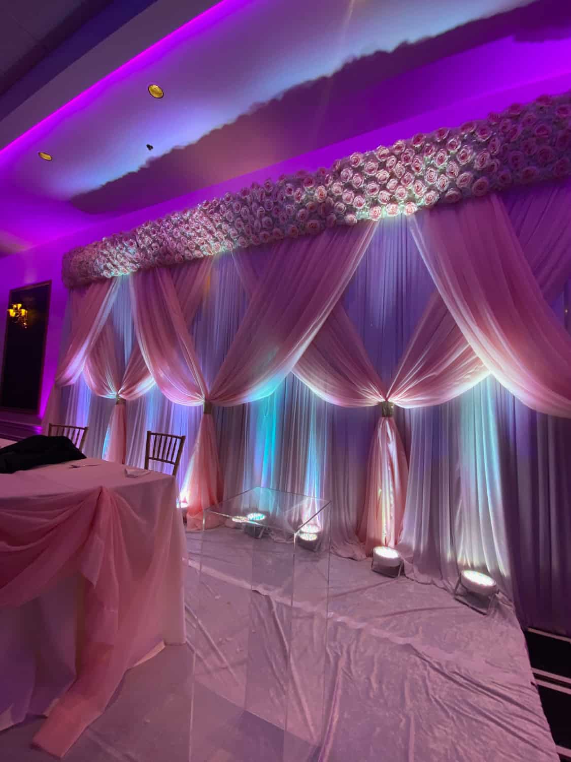 Beautifully decorated event backdrop with draped fabric and floral accents.