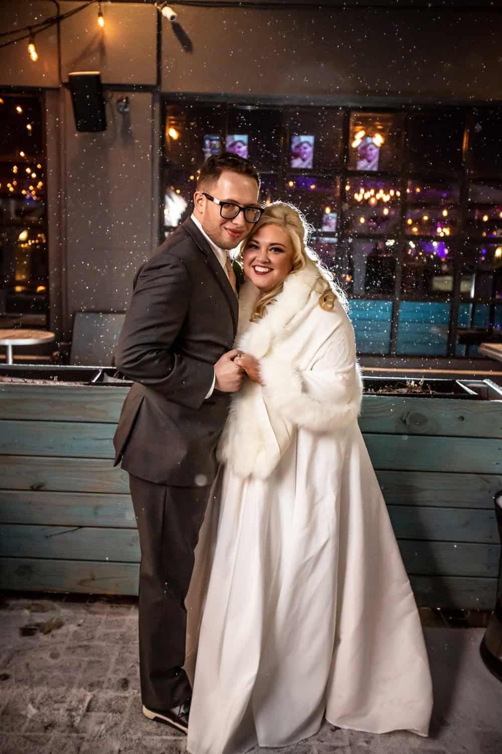 Happy couple at wedding reception with city lights background.