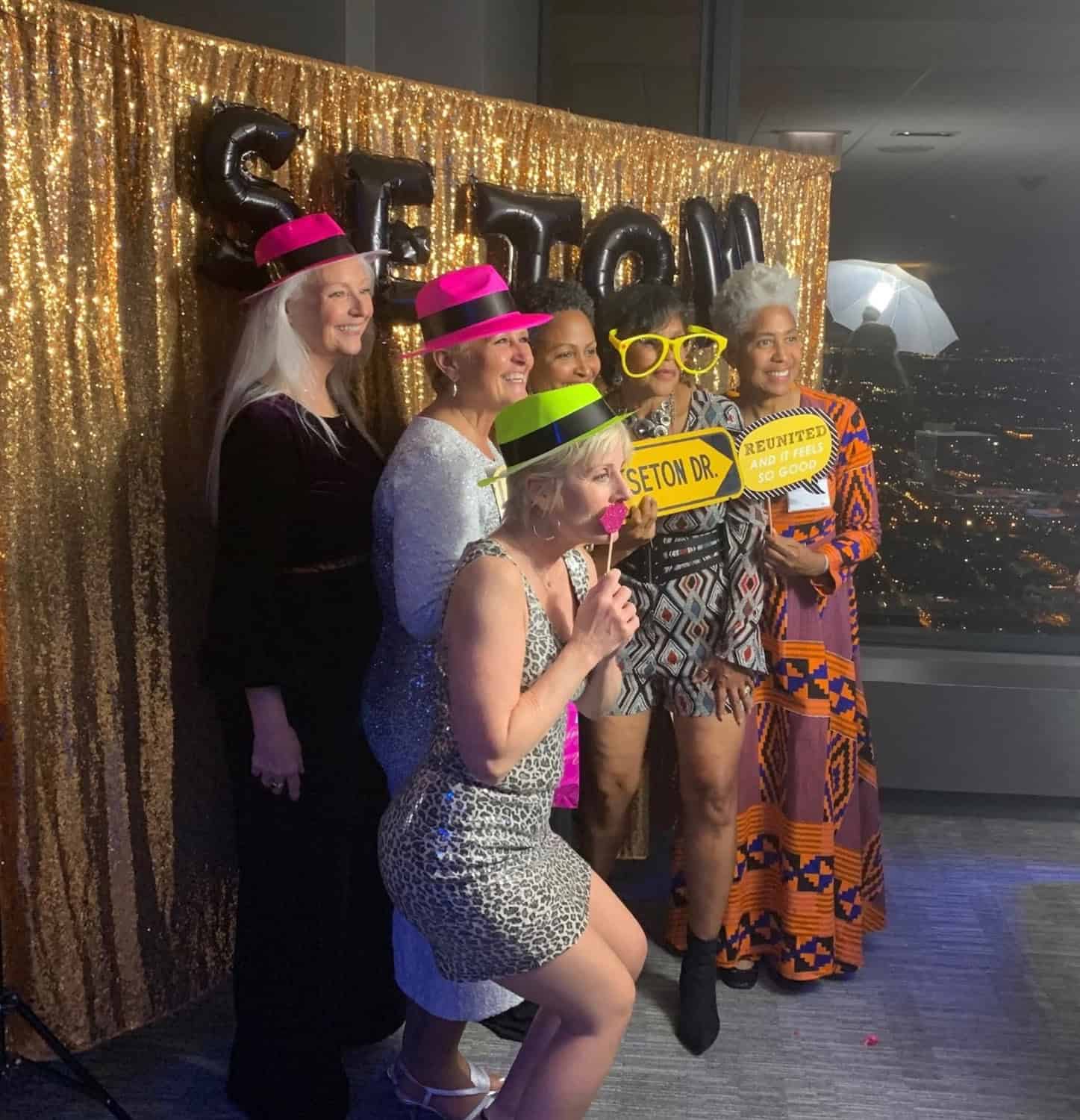 Group of women celebrating with fun props at event.