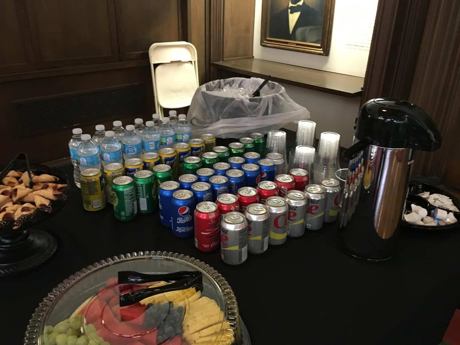 Assorted canned drinks, bottled water, and coffee on a black table.